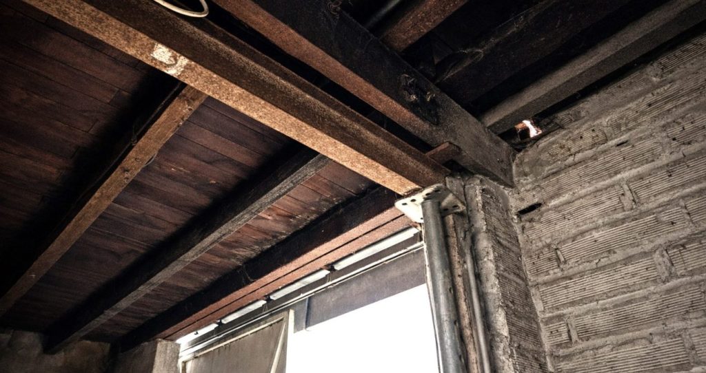 Poutre métallique légèrement rouillée dans un bâtiment ancien, montrant une corrosion superficielle en milieu sec.
