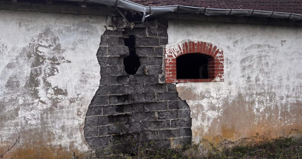 Mur ancien en mâchefer présentant une forte dégradation avec érosion du matériau, illustrant la sensibilité à l’humidité et la porosité du m