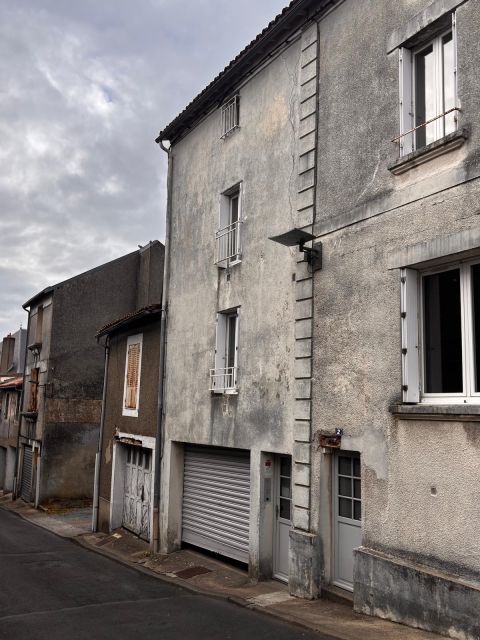 Vue d’ensemble d’une rue en pente avec plusieurs maisons mitoyennes, dont un bâtiment présentant une fissure verticale en façade et des signes de vieillissement général.