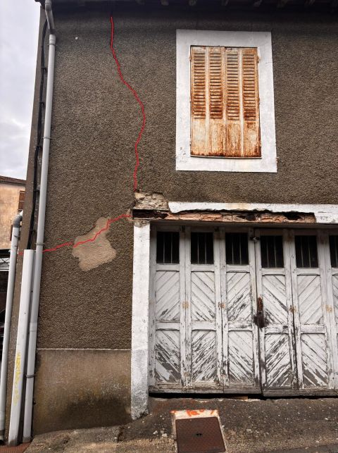 Façade avec fissures mises en évidence en rouge, montrant une fissuration principale verticale et une fissure secondaire horizontale au niveau du linteau, illustrant un point de concentration des efforts.